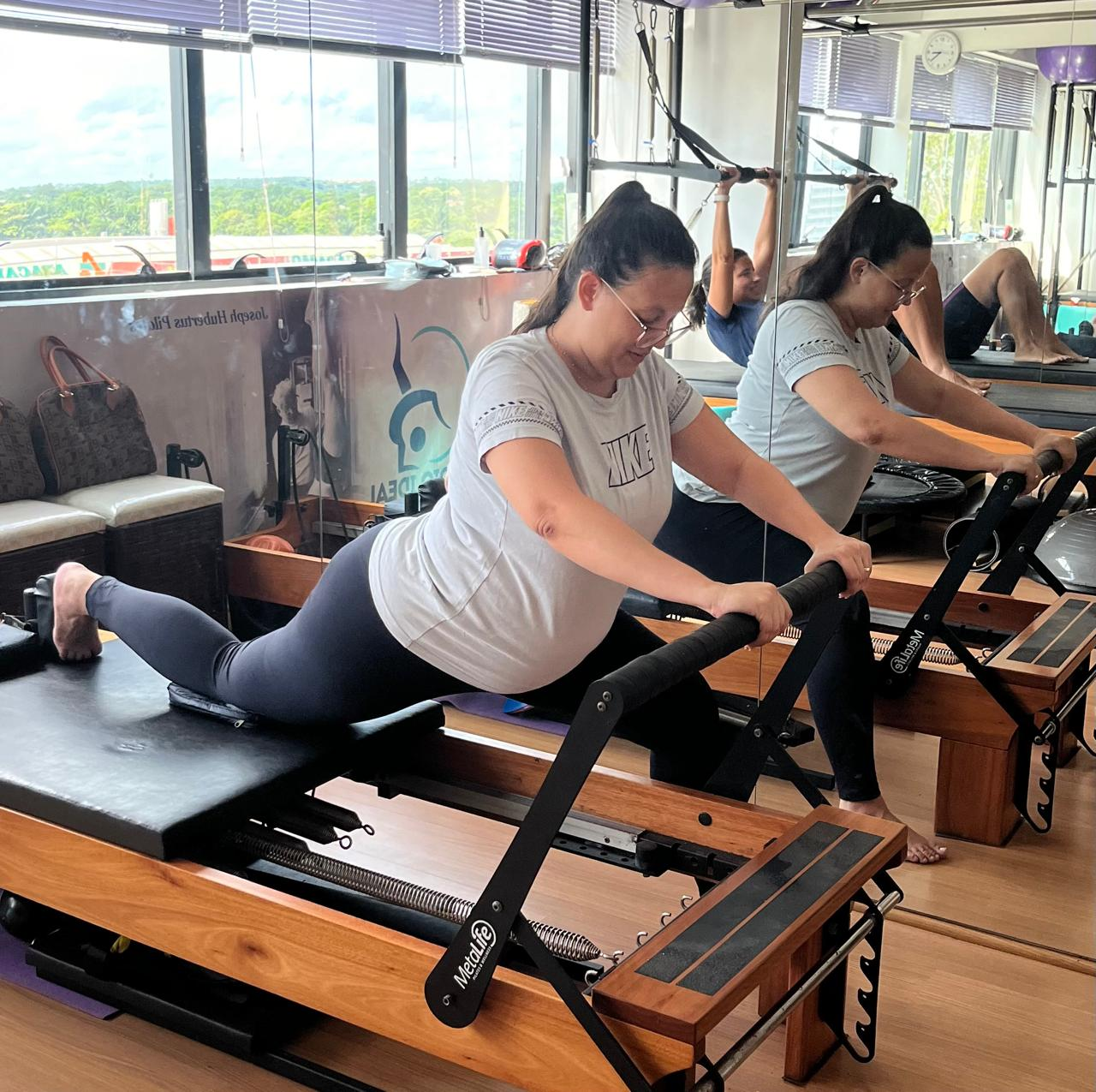 Gestante praticando Pilates no reformer durante aula orientada